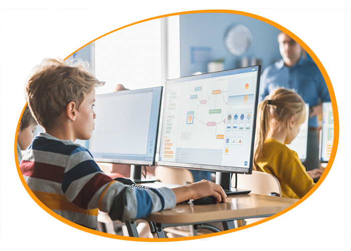 A young child working on a computer while being taught in class.